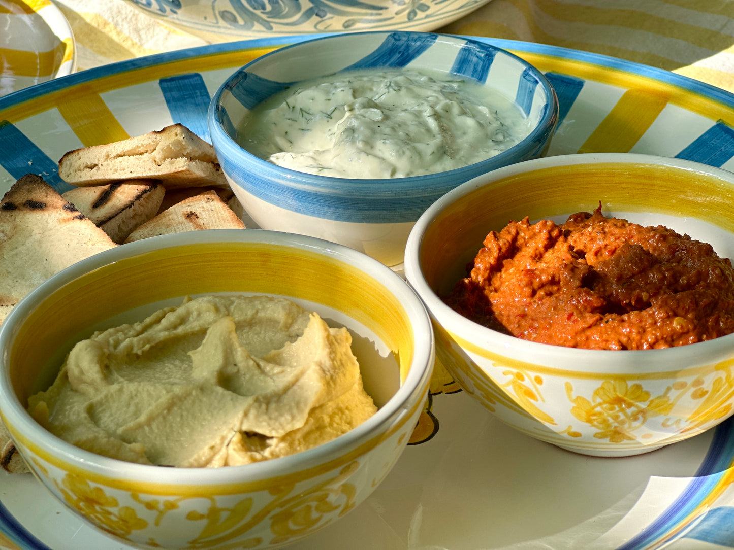 Kleine handbemalte sizilianische Keramikschüsseln mit gelben Ornamenten auf einer Servierplatte mit sommerlichen Dips