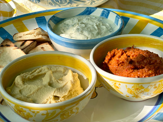 Kleine handbemalte sizilianische Keramikschüsseln mit gelben Ornamenten auf einer Servierplatte mit sommerlichen Dips