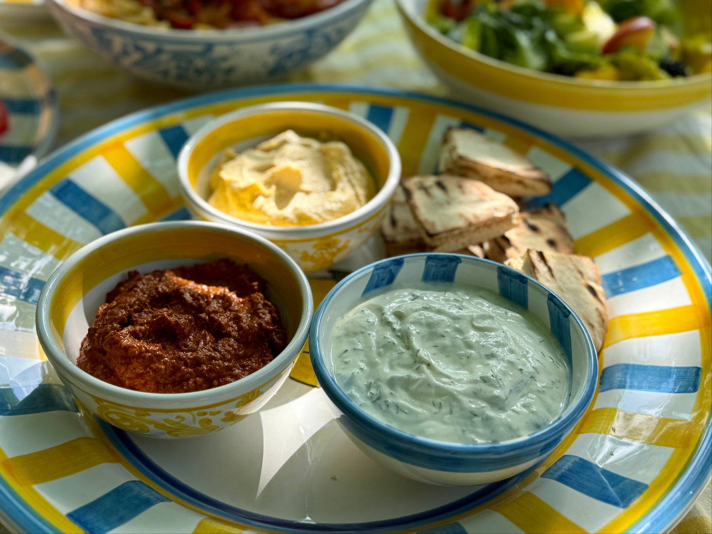 Verschiedene Dips in handbemalten kleinen Keramikschalen mit blau-weissen Streifen