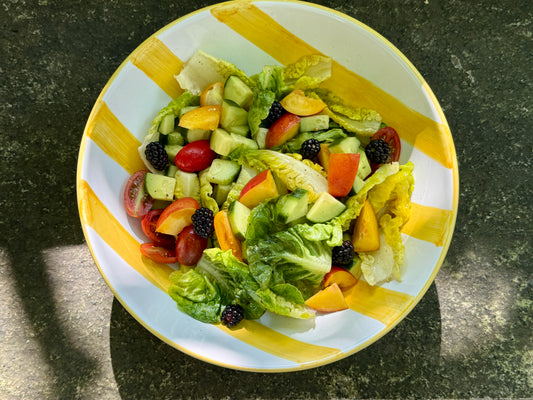 Handbemalte gelb-weiss gestreifte Salatschüssel mit sommerlichem Salat