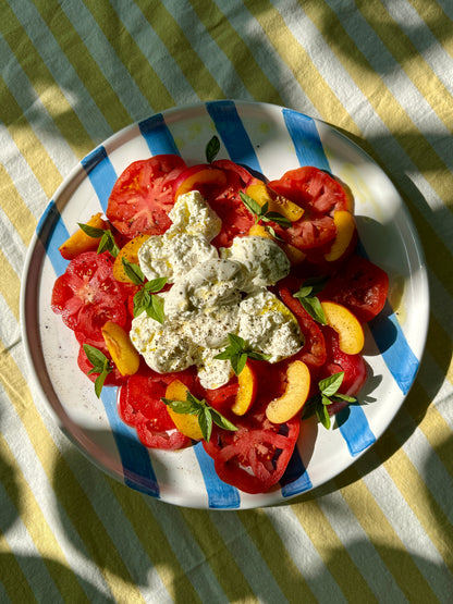 Handbemalte sizilianische Servierplatte aus Keramik, blau-weiss gestreift, mit sommerlichem Caprese Salat und Pfirsichen